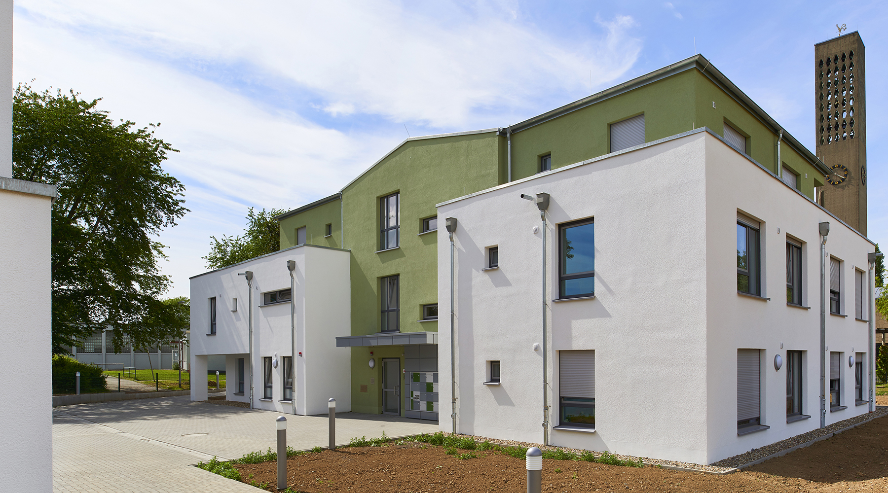 Das Gebäude ist in drei Elemente unterteilt, wobei die Seitenflügel weiß und die Mitte grün sind.