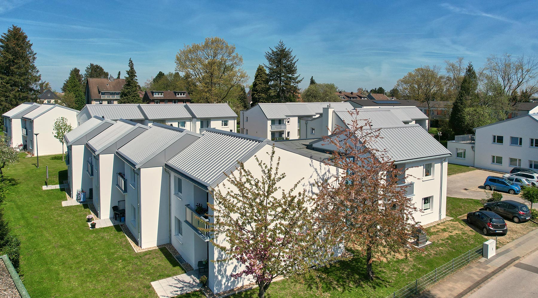 Wohnanlage am Reulert in Aachen. Draufsicht eines Wohnkomplexes: Weiße Gebäude mit grauem Spitzdach und offenem Garten.